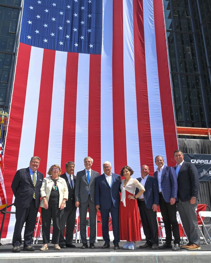 Photograph from topping out ceremony. From left, State Senator Peter Harckham; Westchester County Director of Operations Joan McDonald; Westchester County Executive George Latimer; White Plains Mayor Tom Roach; Louis R. Cappelli, President, Cappelli Organization; Vanessa Racci, vocalist who sang the National Anthem; Todd Rechler, Chief Construction & Development Officer, RXR; Bradley Korman, co-CEO, Korman Communities and Joseph Graziose, Executive Vice President of Development Services, RXR